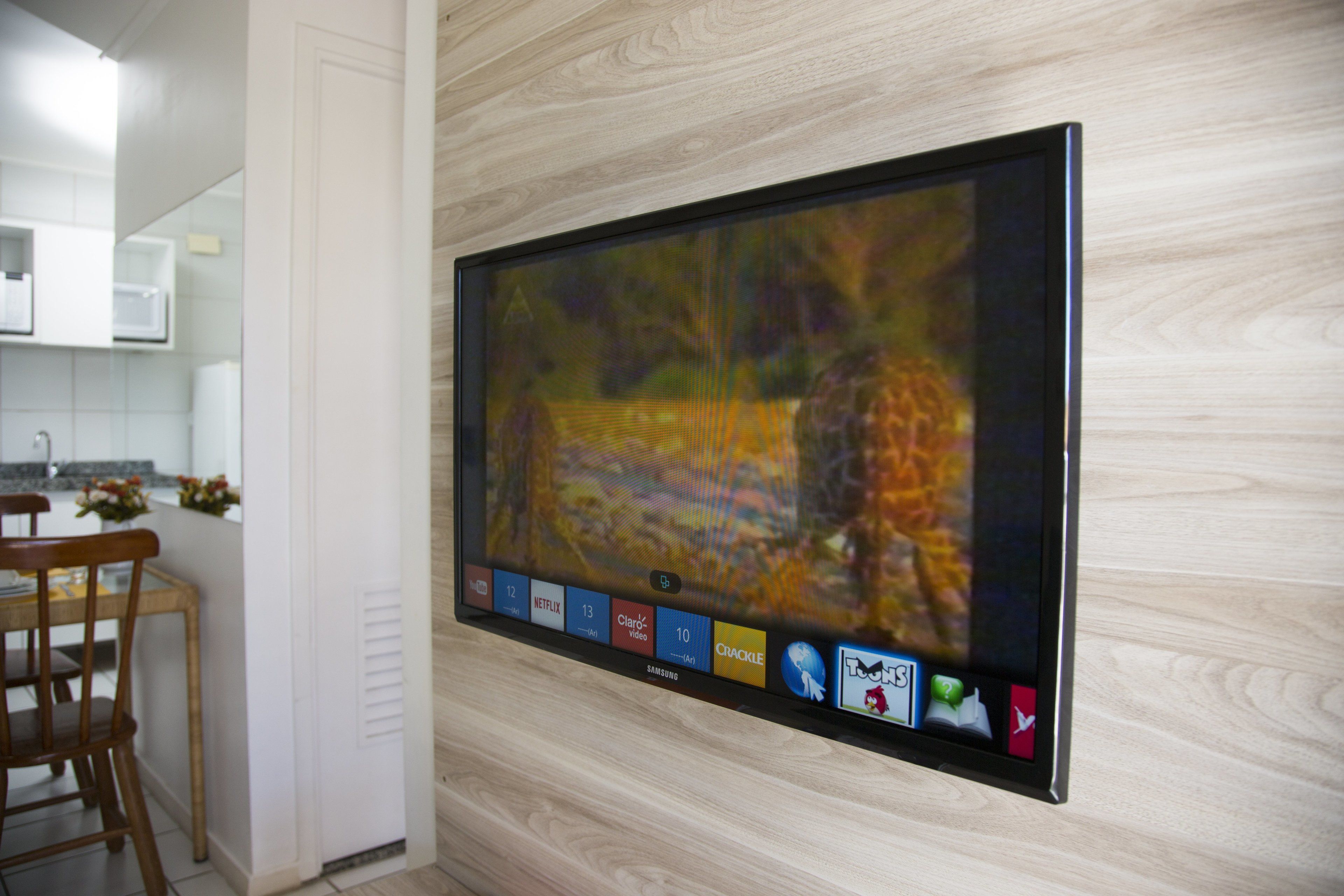 Televisão de tela plana fixada em parede com design de painel de madeira.