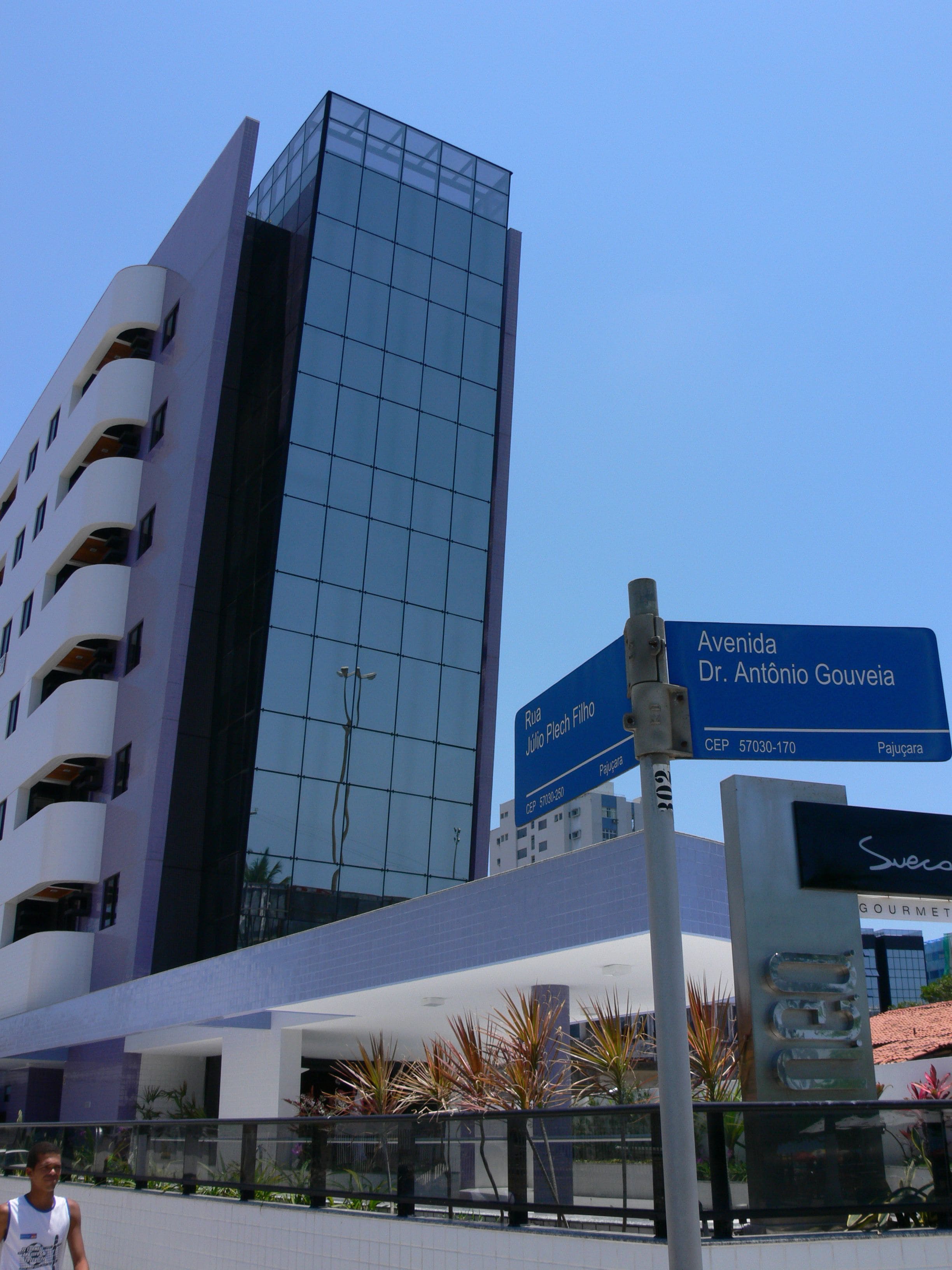 A modern building with a glass facade and a sign indicating Avenida Dr. Antônio Gouveia.
