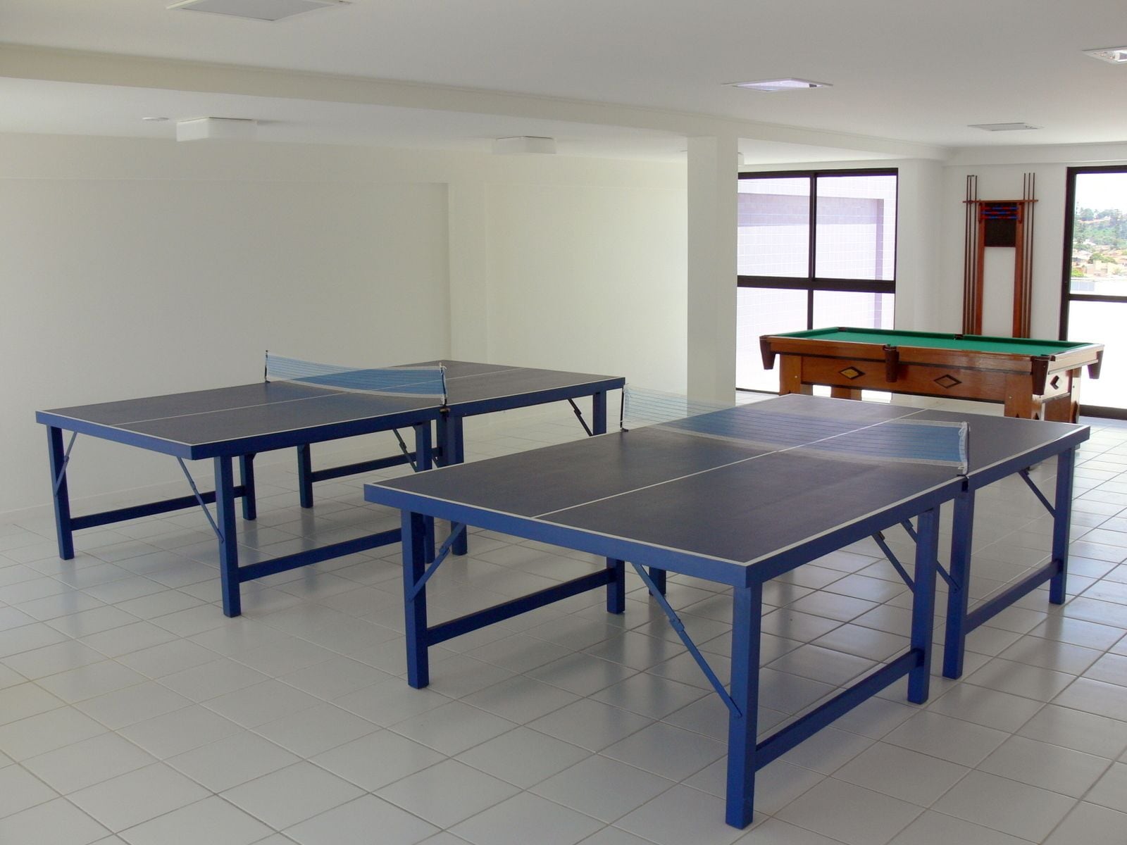 A room with two ping pong tables and a pool table.