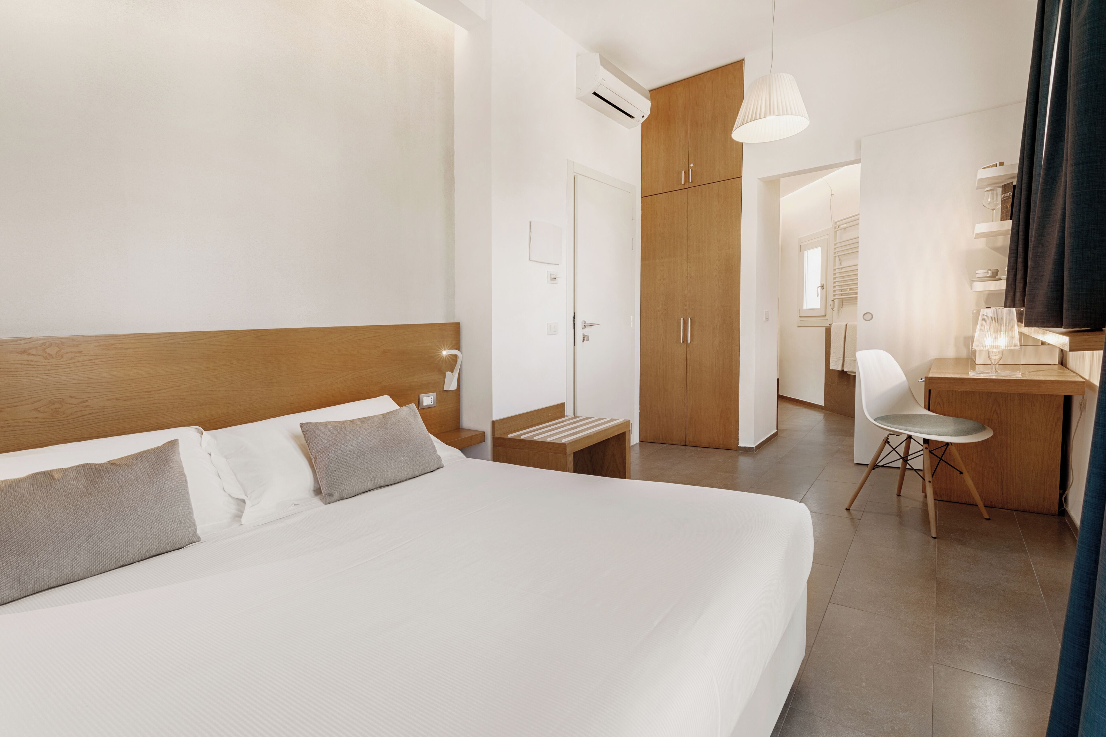 Una habitación de hotel con una cama grande, un escritorio, una silla y un armario.