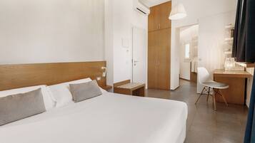 Una habitación de hotel con una cama grande, un escritorio, una silla y un armario.