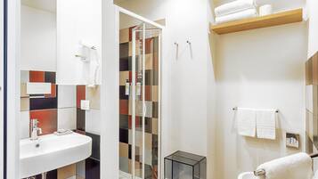 Un baño moderno con cabina de ducha de vidrio, lavamanos y retrete.