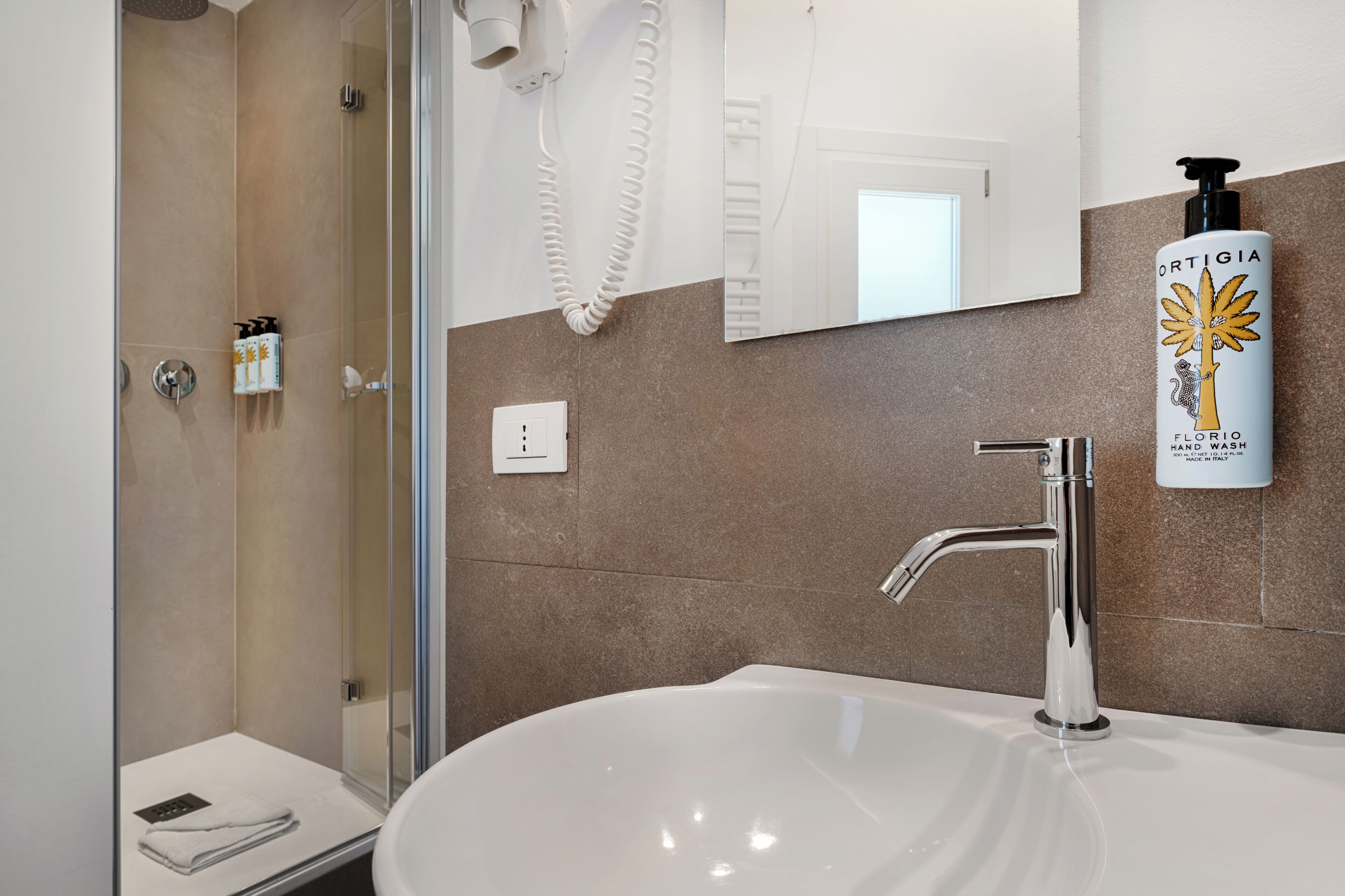 A modern bathroom with a sink, mirror, and shower.