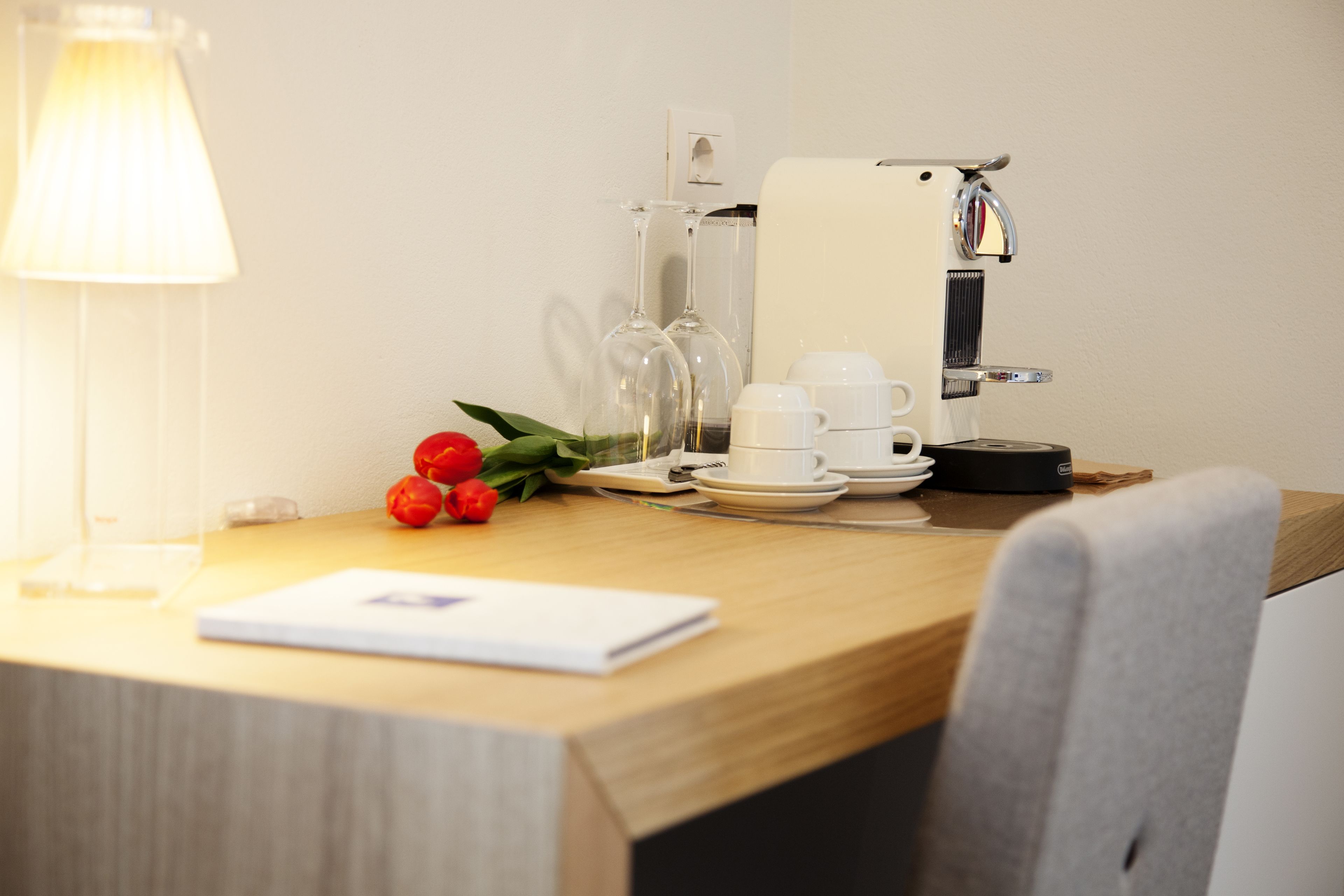 A wooden table with a coffee machine, cups, and a notebook.