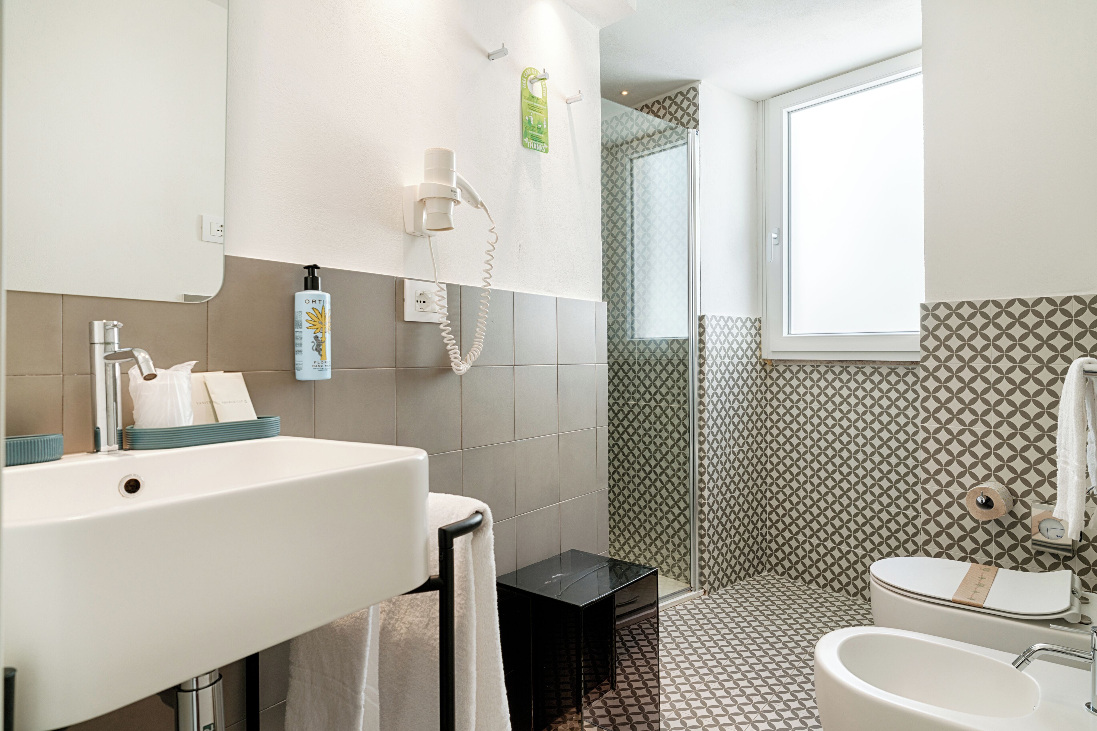Un baño con lavamanos, espejo, toallero y zona de ducha.