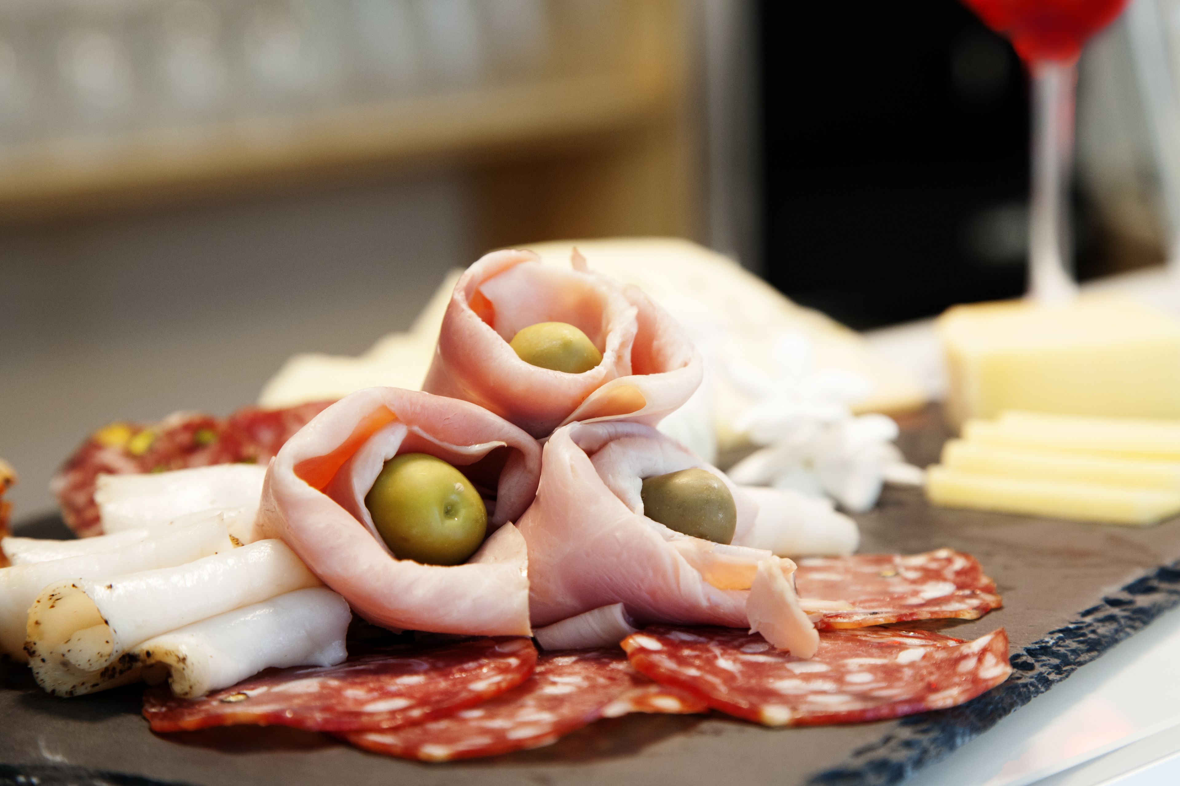Une planche de charcuterie avec différentes sortes de viandes, de fromages et d’olives.