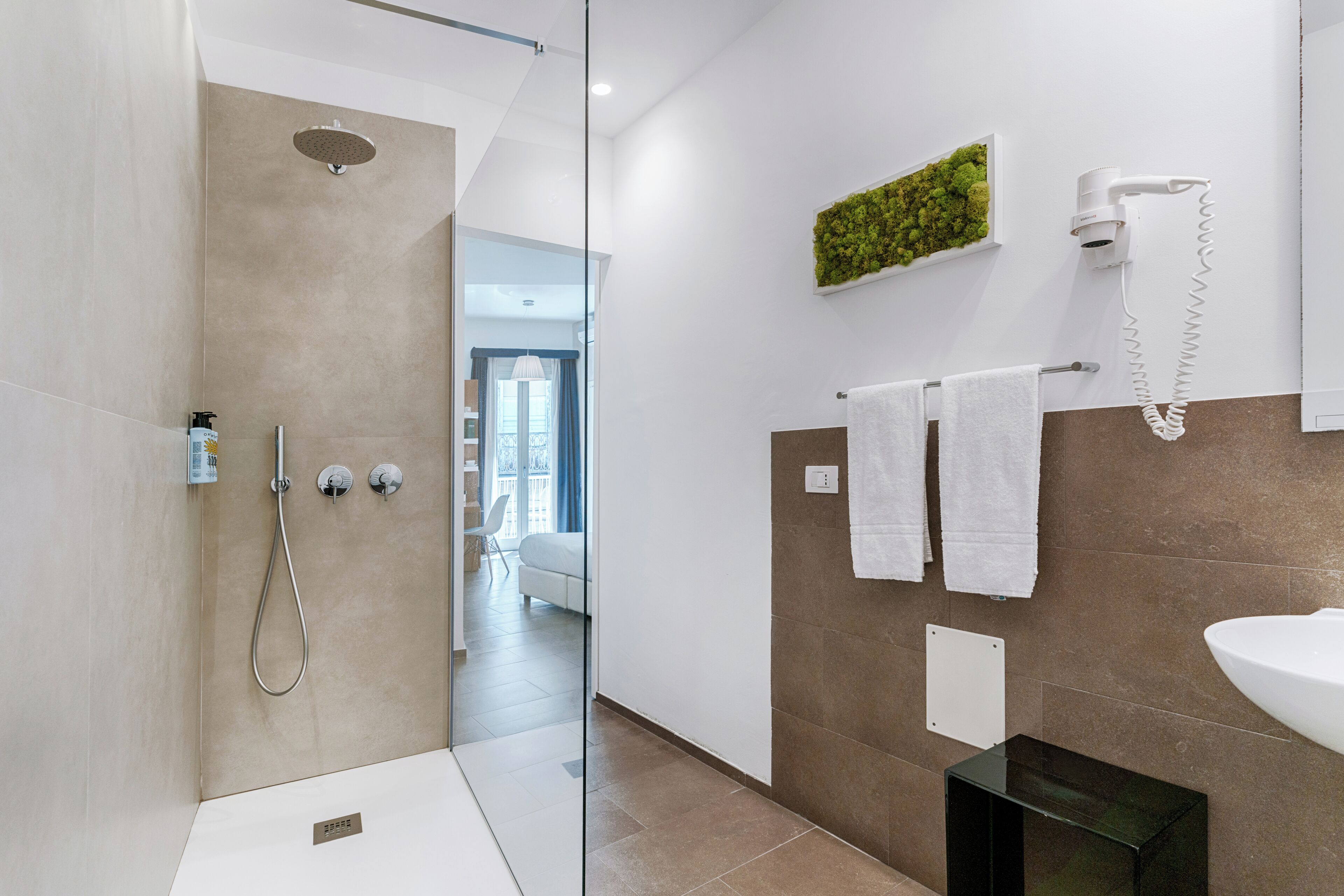 Een moderne badkamer met een douche, een haardroger en een wastafel.