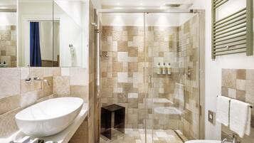 A modern bathroom with a large oval sink, a glass-enclosed shower, and a separate pedestal sink.