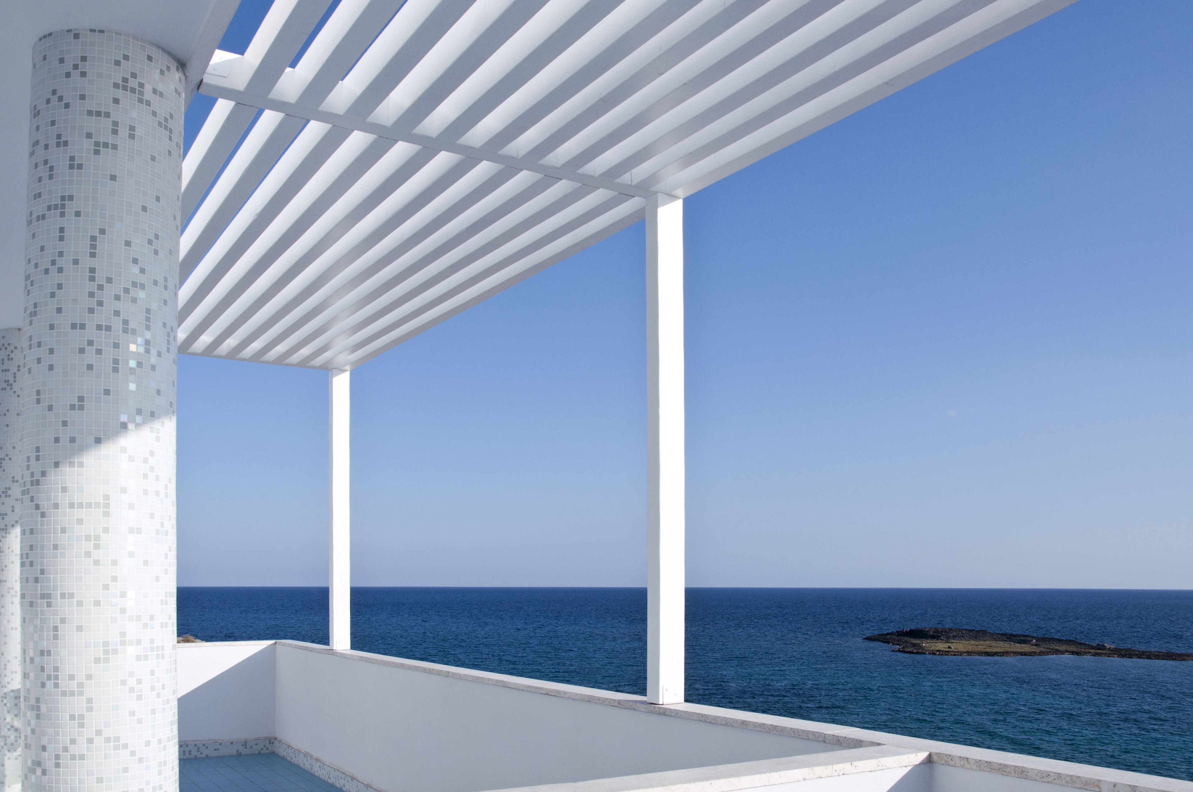 A balcony with a view of the sea and a tiled column.