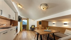 A modern kitchen with wooden cabinets, a built-in oven, and a sink. There is a dining area with a wooden table and benches.