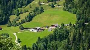 A rural property with a large house, solar panels, and a surrounding green landscape.