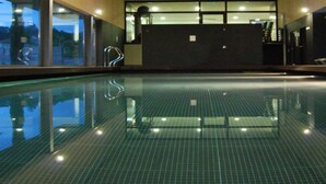 An indoor swimming pool with clear water, a tiled floor, and a reception area with a counter and chairs. - Hotel Rural Quinta Da Cruz (Amarante)
