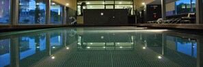 Una piscina al aire libre, sombrillas, sillones reclinables de piscina