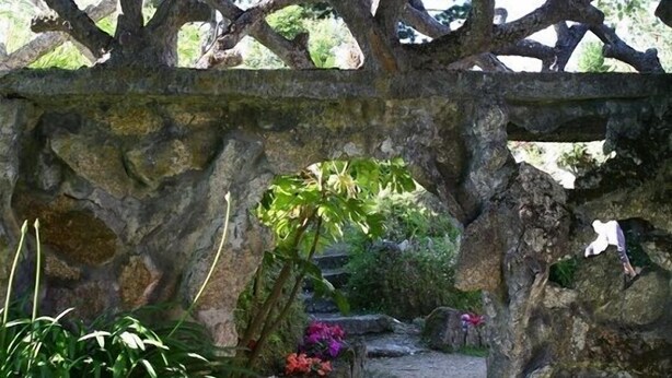 A stone archway with a pathway leading through it, surrounded by greenery and flowers. - Hotel Rural Quinta Da Cruz (Amarante)