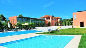A swimming pool with lounge chairs and umbrellas, surrounded by buildings with a modern design. - Hotel Rural Quinta Da Cruz (Amarante)