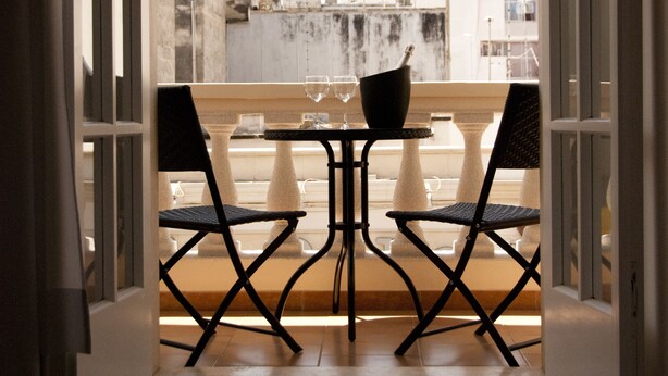 An open balcony with two chairs and a table, overlooking a cityscape. - Il Corso (Porto Cesareo)