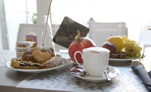 A breakfast table with pastries, a cup of coffee, and a plate of fruit. - Il Corso (Porto Cesareo)