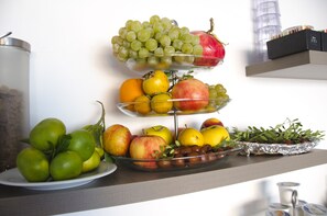 A fruit display with apples, oranges, and grapes on a shelf. - Il Corso (Porto Cesareo)