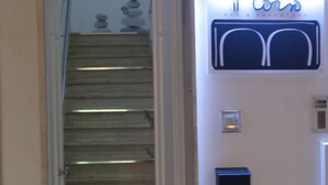 A hotel entrance with a staircase leading to the second floor. There is a neon sign above the door that reads "Il Corno Bed & Breakfast." - Il Corso (Porto Cesareo)