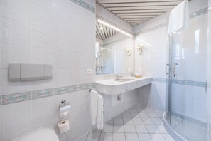 A modern bathroom with a glass shower enclosure, a white sink, and a toilet.