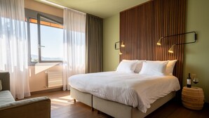 Une chambre d’hôtel avec un grand lit, une vue par la fenêtre et un mur recouvert de panneaux de bois.