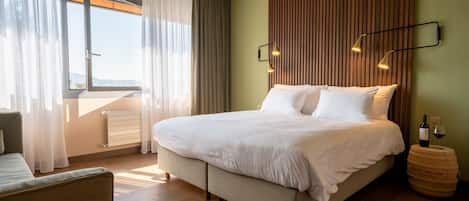 Habitación de hotel con una cama grande, vista por la ventana y un panel de pared de madera.