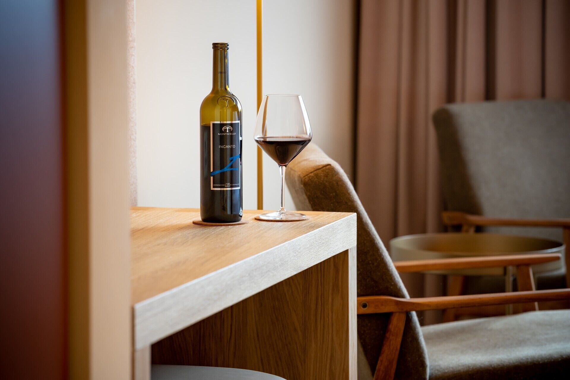 Una mesa de madera con una botella de vino y una copa de vino tinto.