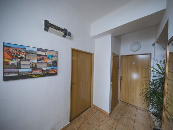 A hallway with wooden doors, a wall-mounted air conditioner, and a collage of photos.