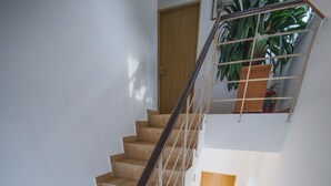 A staircase with a metal railing, beige tiles, and a wooden door at the top. - Pension Nika (Prague)