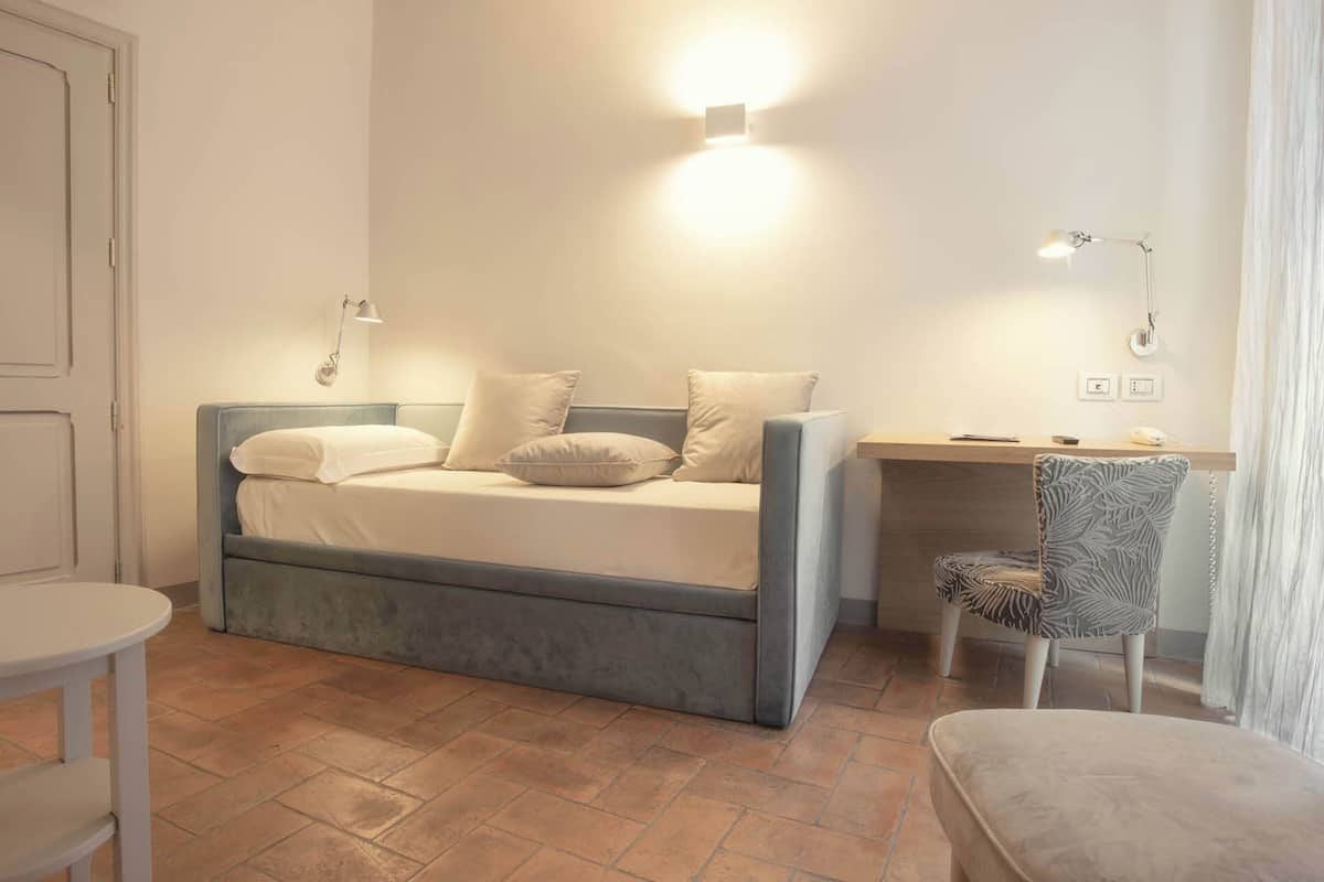 A bedroom with a bed, desk, chair, and a small round table.