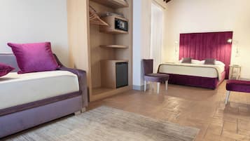 Ein Schlafzimmer mit Bett, Sessel, kleinem Tisch, einer Ablage mit einer Mikrowelle und einem Kleiderschrank.