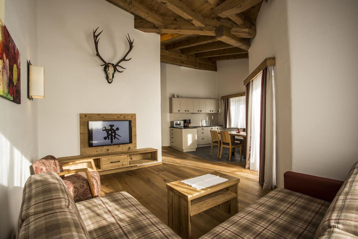 A living room with a wooden ceiling, a mounted deer head, a television, and a sofa.