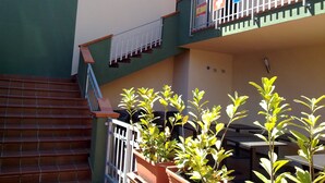 A multi-level building with a staircase, potted plants, and a sign indicating a reception area. - La Locanda del Mare (Siniscola)