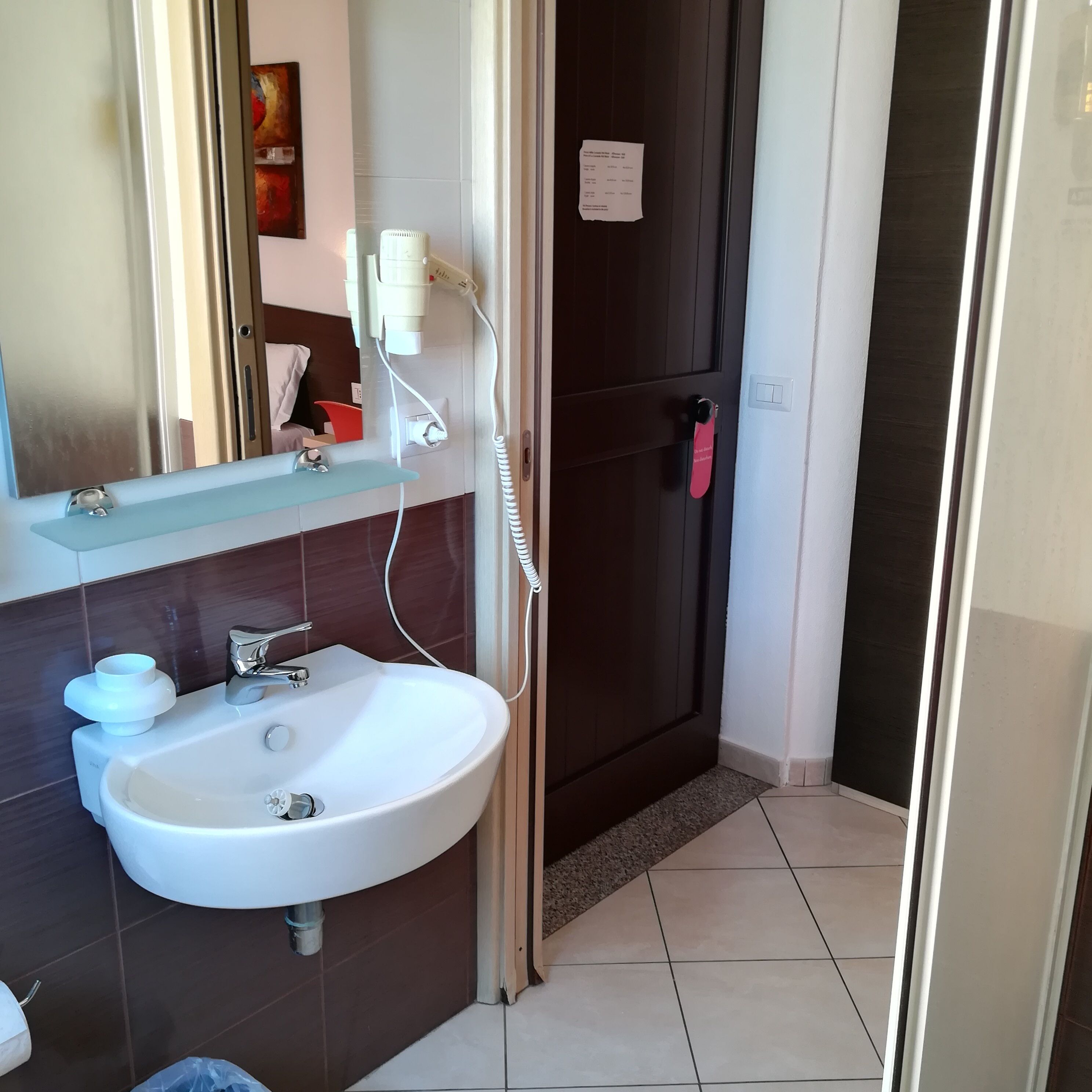 A bathroom with a white sink, a mirror, and a dark door.