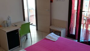 A hotel room with a bed, a desk, a chair, a TV, and a window with curtains. - La Locanda del Mare (Siniscola)