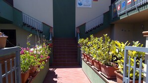 A narrow corridor with potted plants on either side, leading to a staircase. - La Locanda del Mare (Siniscola)