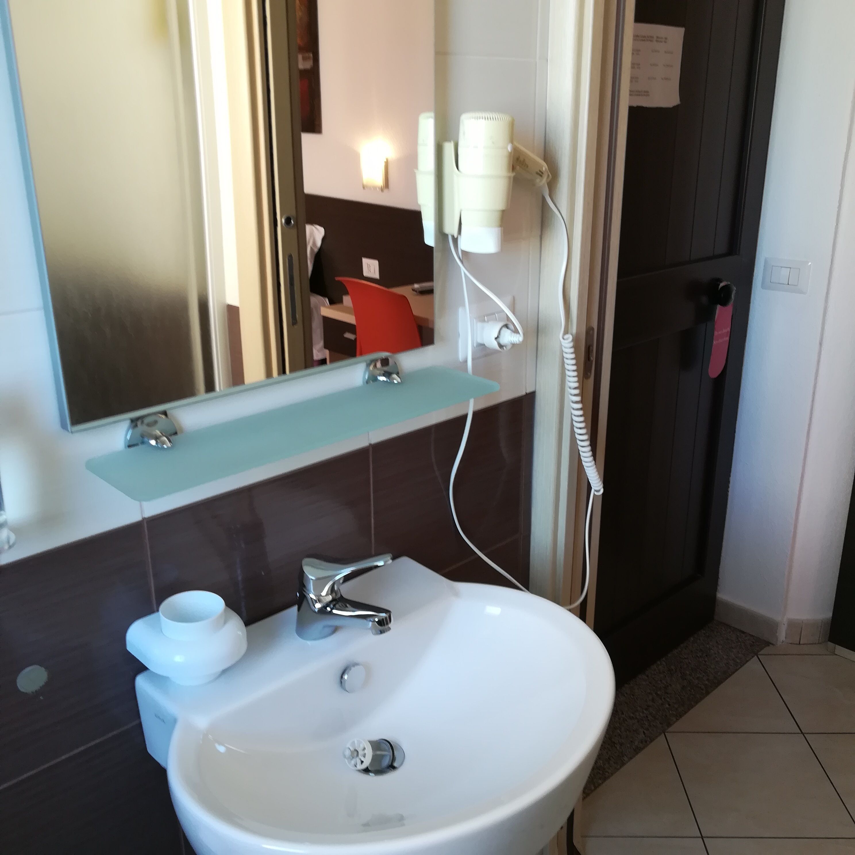 Une salle de bain avec un lavabo blanc, un miroir et un porte-serviettes.