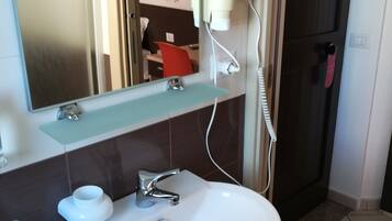 Une salle de bain avec un lavabo blanc, un miroir et un porte-serviettes.