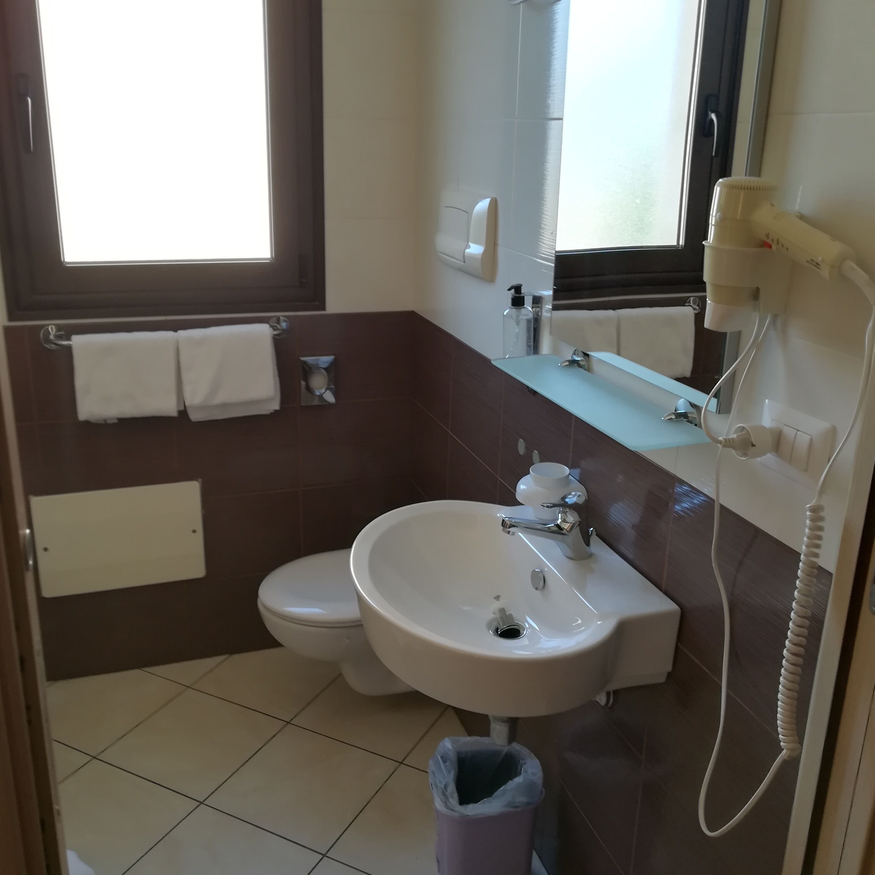 Ein Badezimmer mit Waschbecken, Toilette und einem Fenster.