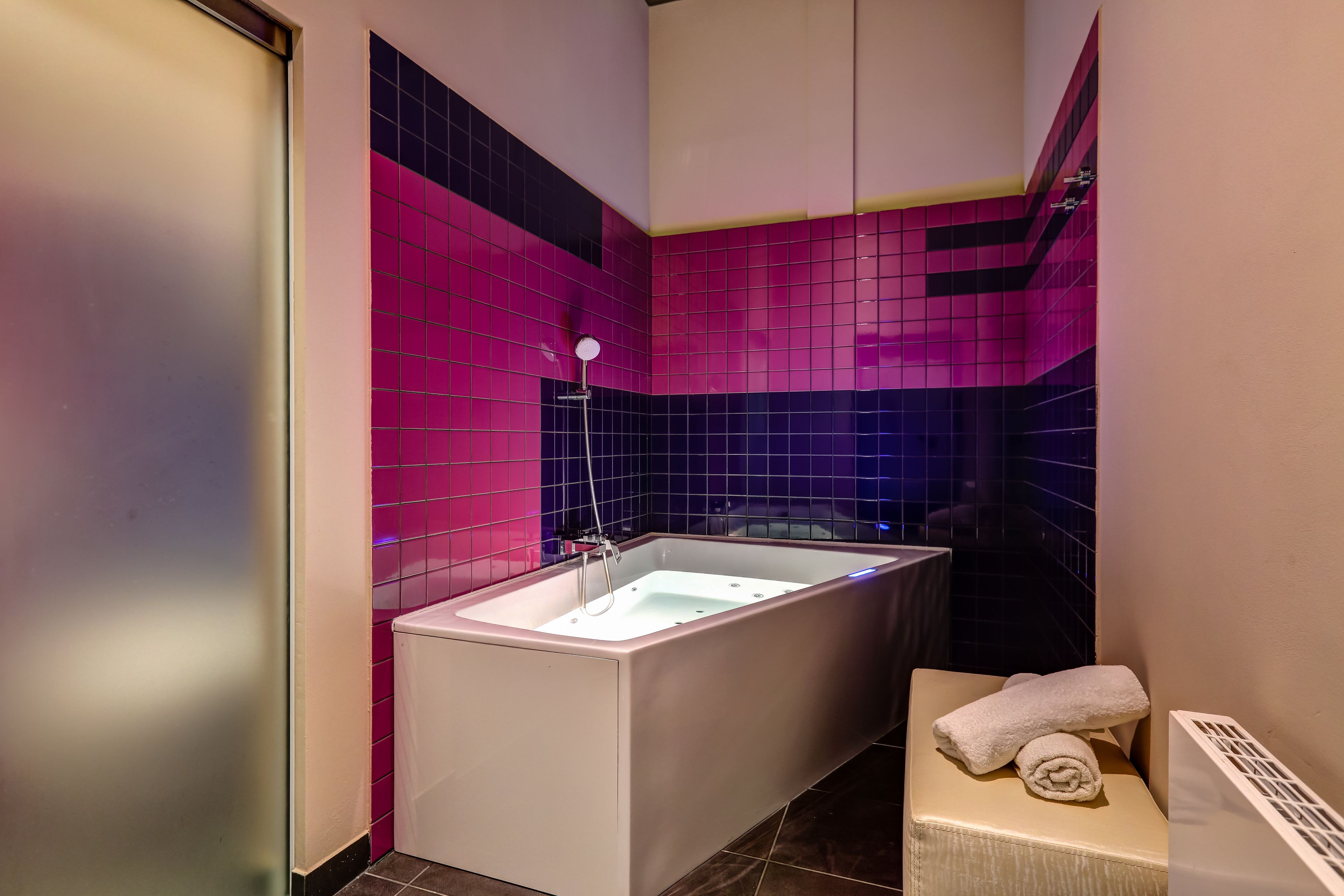 Un baño con una bañera independiente, un perchero para toallas y una pared con azulejos.