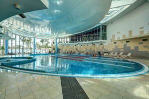 Swim laps in the pool surrounded by a spacious area with lounge chairs and a seating area offering a view.