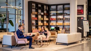 A modern lobby with seating areas, a large bookshelf, and a television.