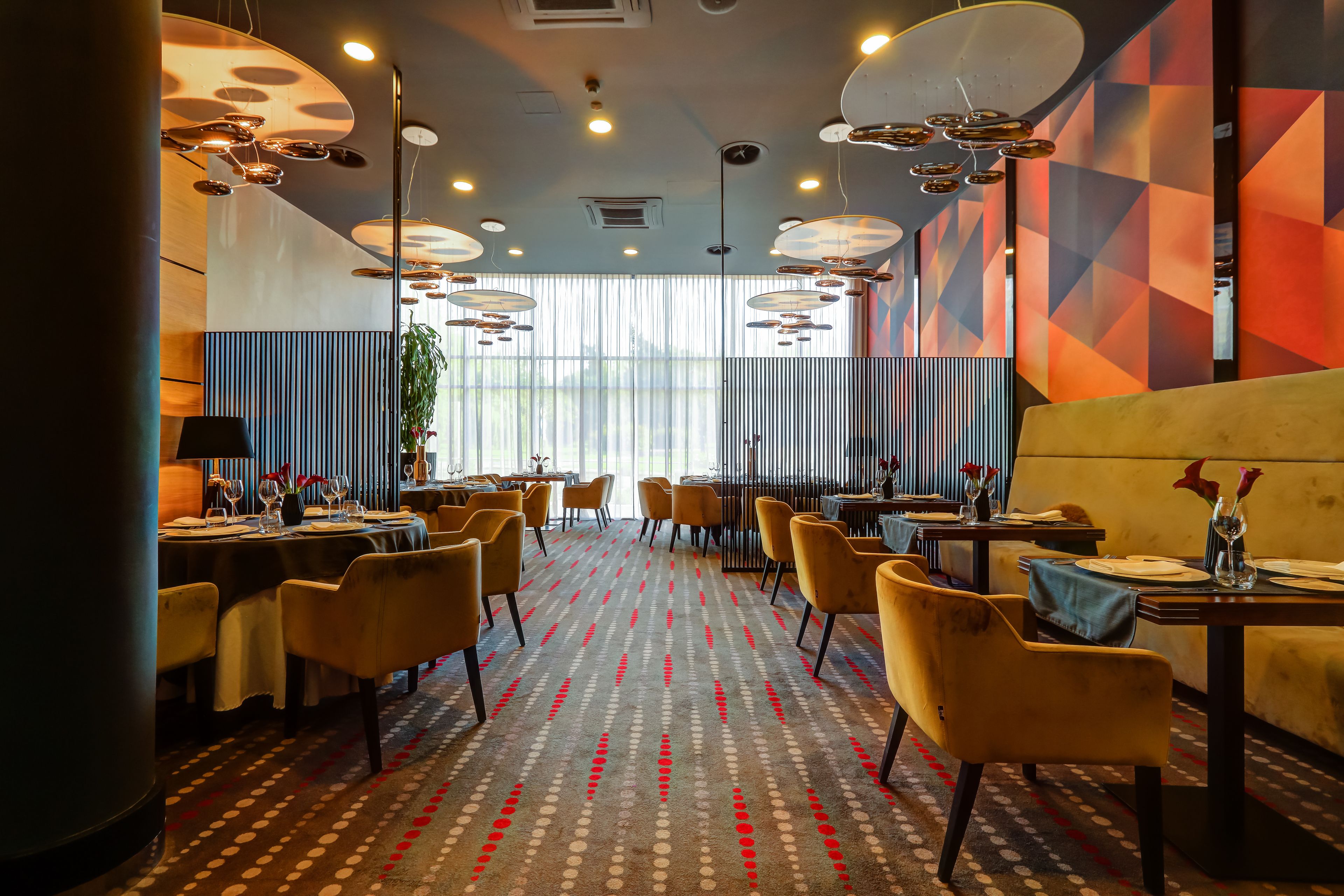 A restaurant with round tables, yellow chairs, and a patterned carpet.