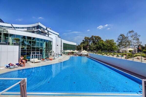 Piscine couverte, piscine extérieure, parasols de plage, chaises longues