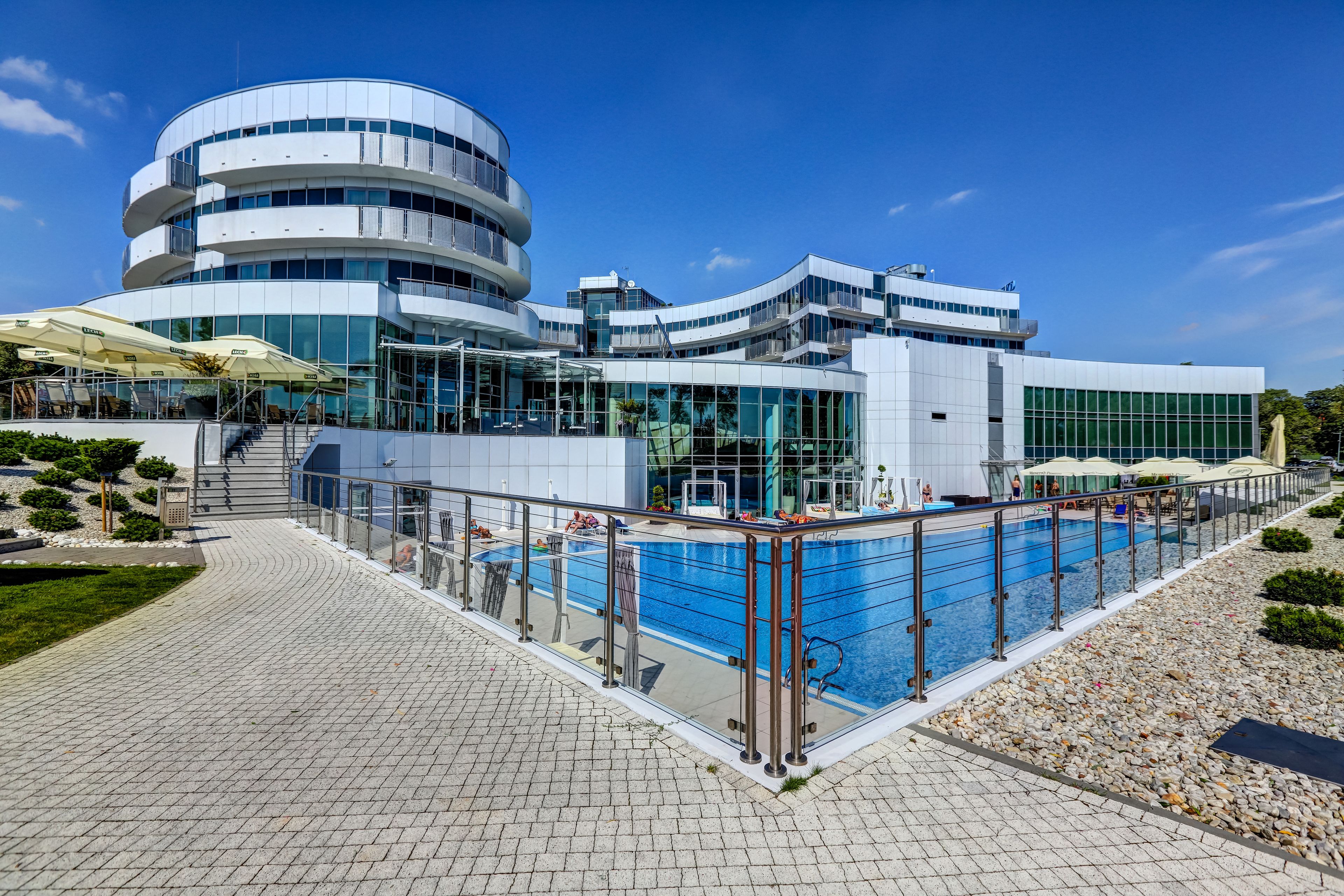 A modern hotel with a pool, outdoor seating, and a well-maintained garden.