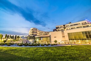 Experience the unique architecture of this hotel, featuring a curved facade and expansive glass windows, set amidst a beautifully manicured lawn.