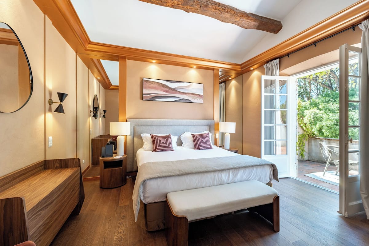 Un dormitorio moderno con una cama grande, piso de madera y vistas al exterior.