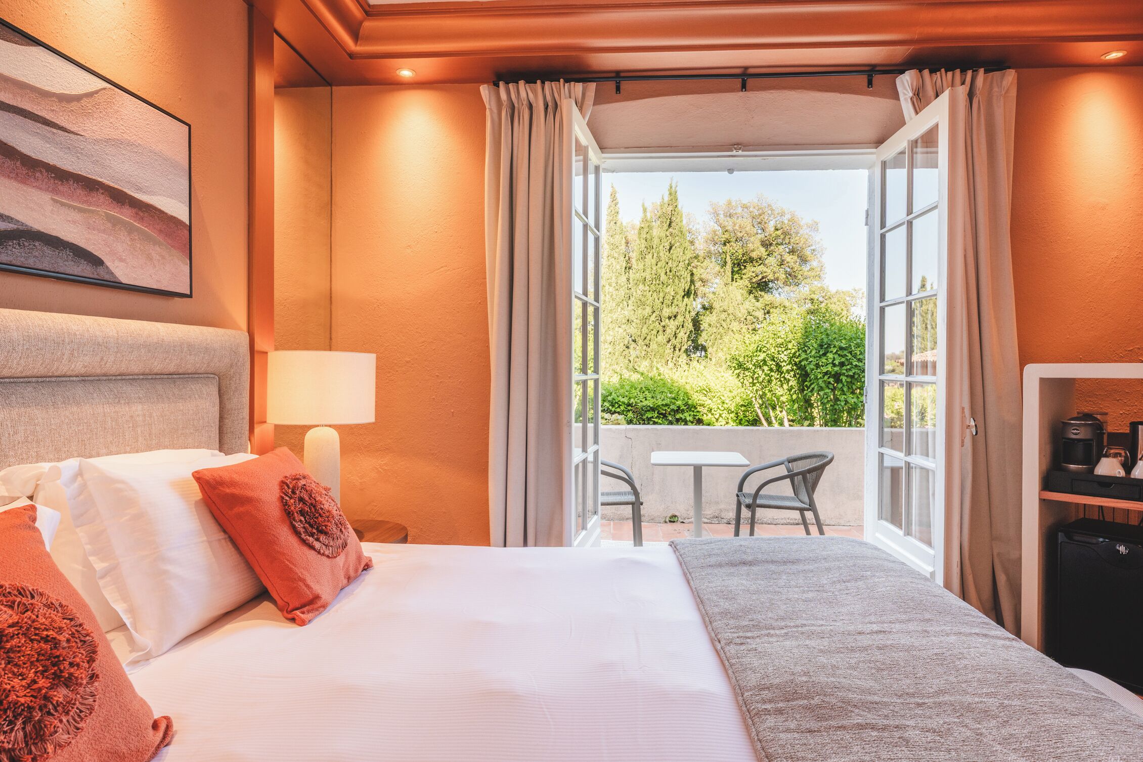Habitación de hotel con cama, escritorio, silla y vistas a la vegetación.