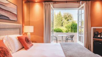 Habitación de hotel con cama, escritorio, silla y vistas a la vegetación.