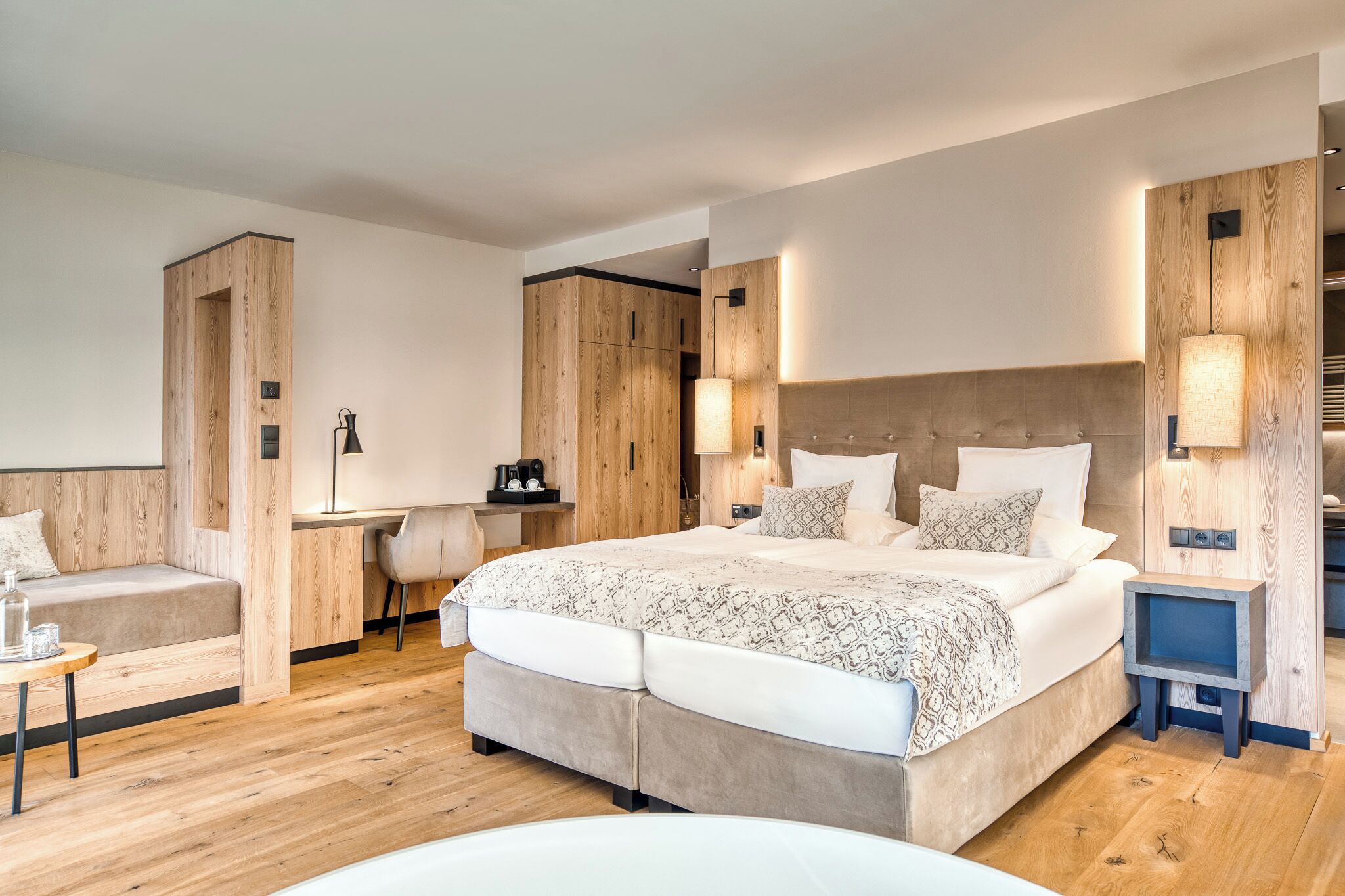 A modern bedroom with a large bed, a desk, and a seating area.